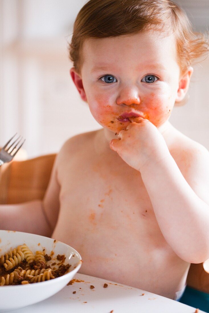 Kleiner Junge isst Fusilli Bolognese