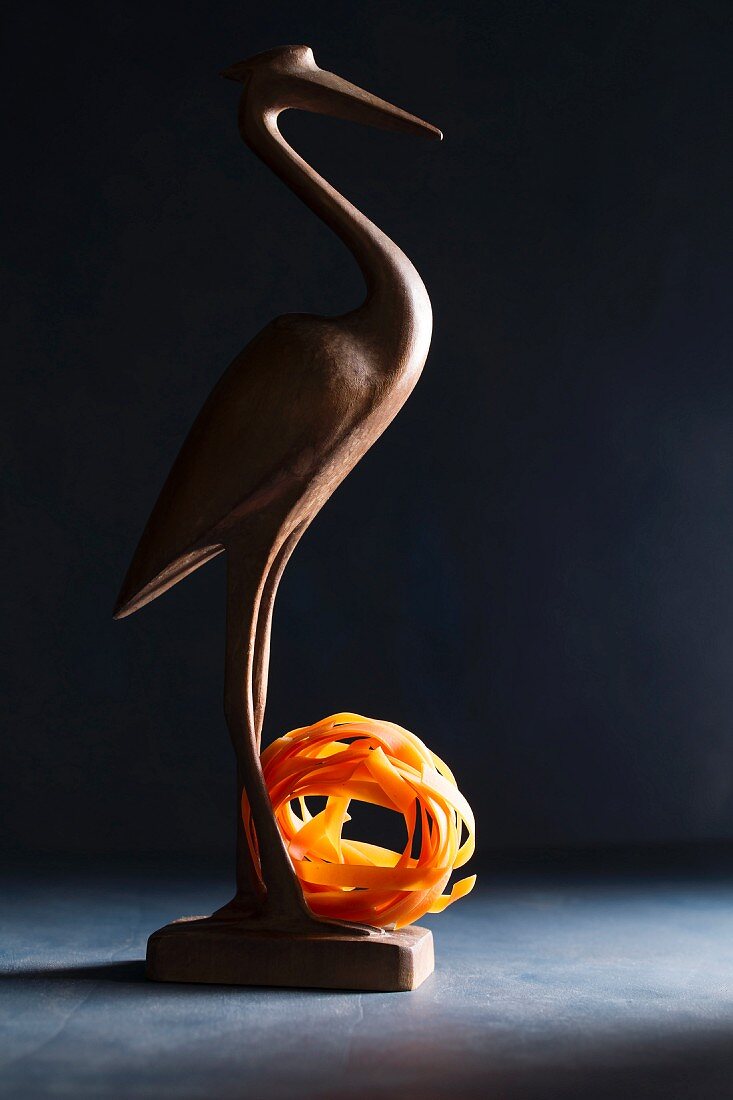 A wooden bird with a nest of tomato tagliatelle
