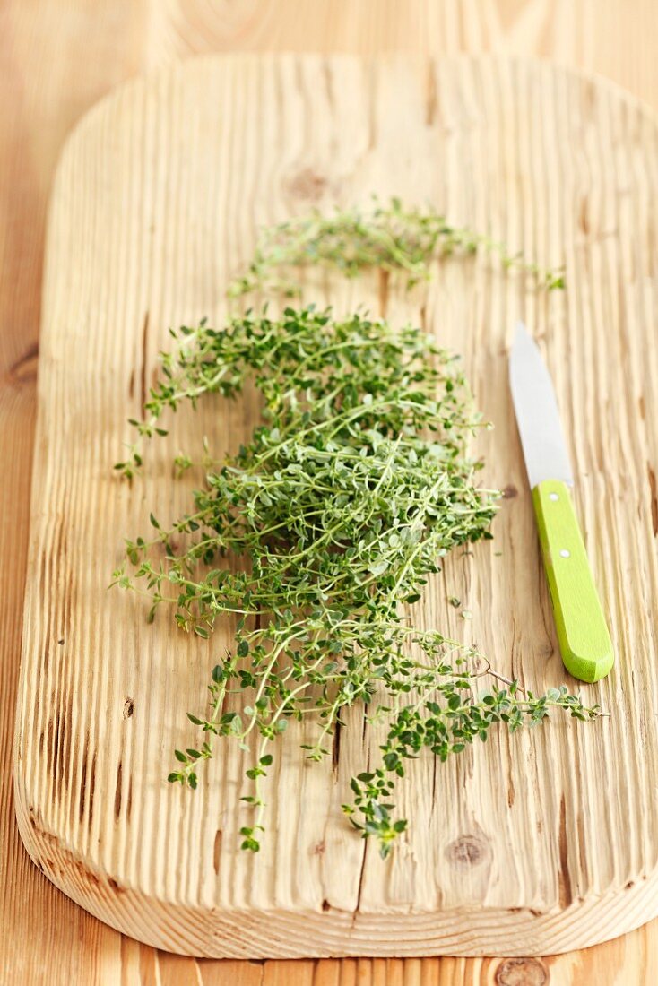 Fresh lemon thyme on a chopping board with a knife