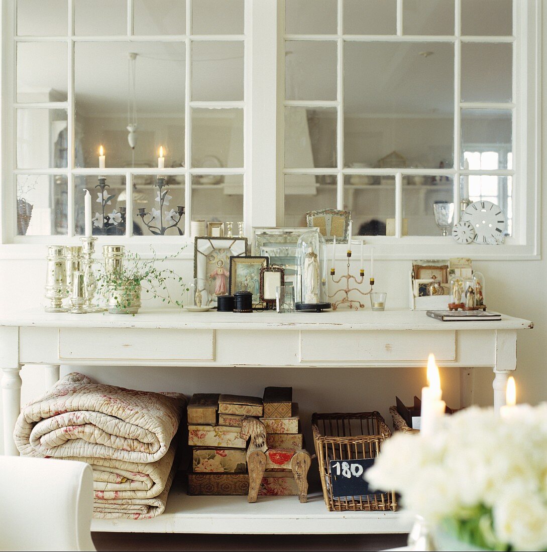 White-painted, country-house table below lattice window looking into adjacent kitchen