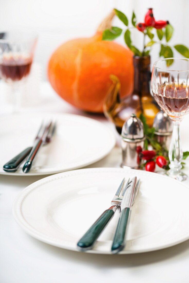 Two place settings on a table with autumnal decorations