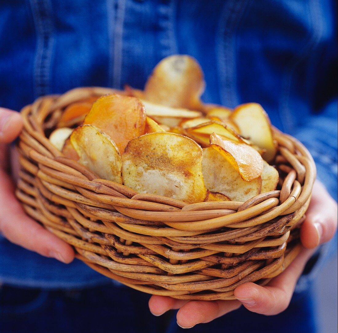 Hände halten Korb mit Kartoffelchips