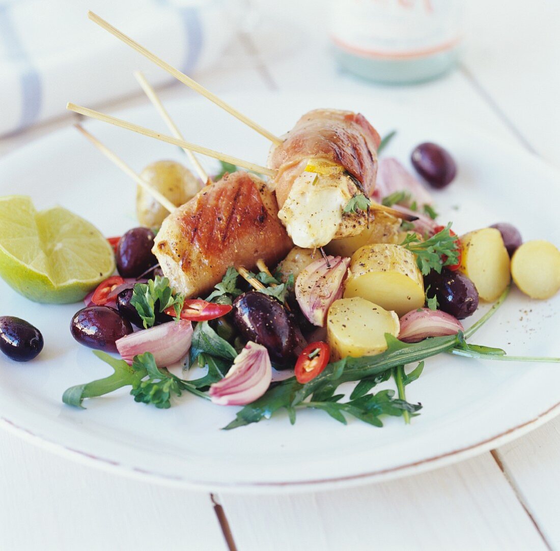 Fish skewers with bacon on potato & olive salad
