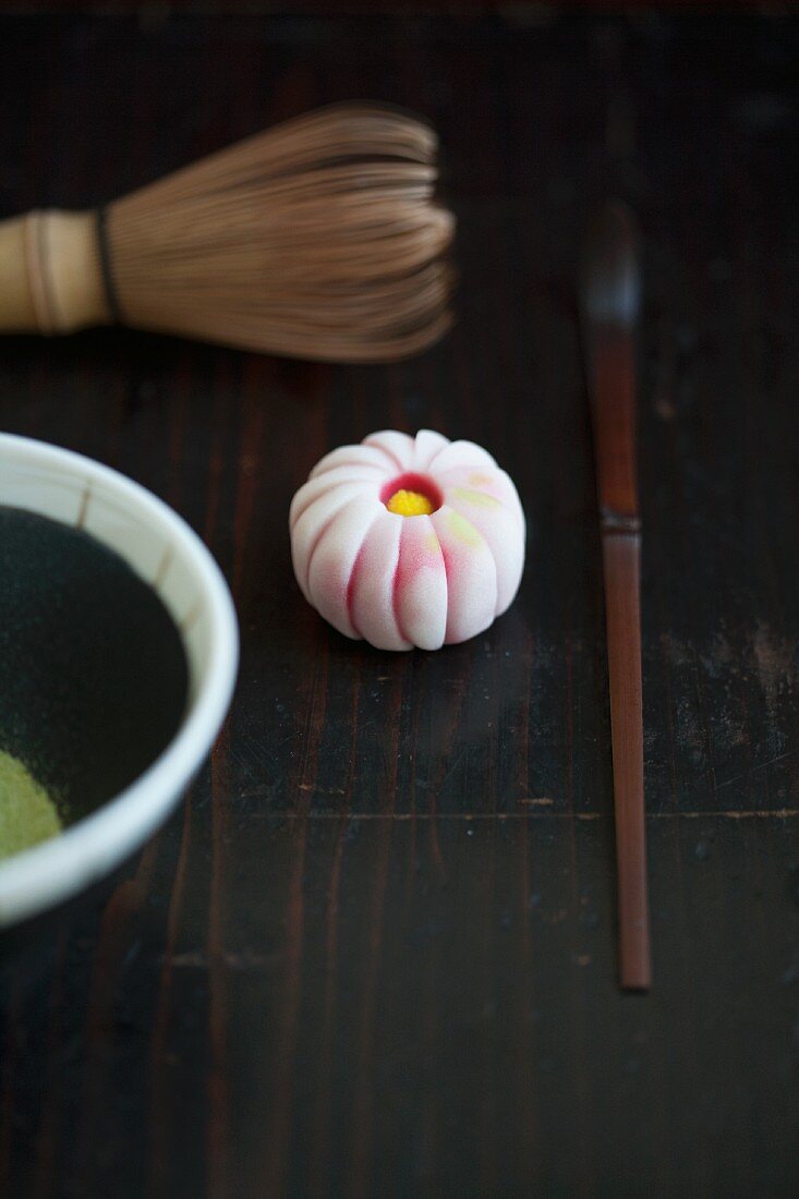 A wagashi chrysanthemum (kiku), a tea whisk, a matcha spoon and matcha tea