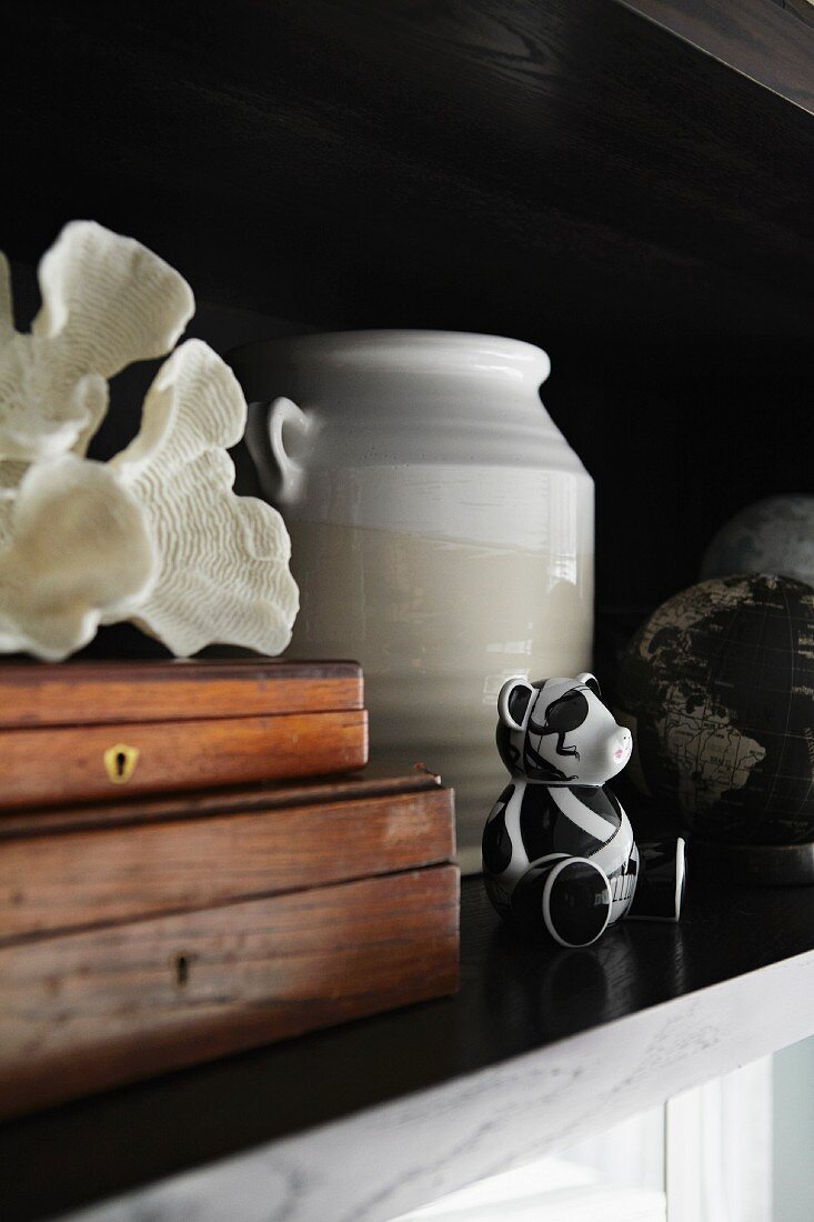 Two wooden boxes, white shell, ceramic vase and small, black and white bear ornament on shelf