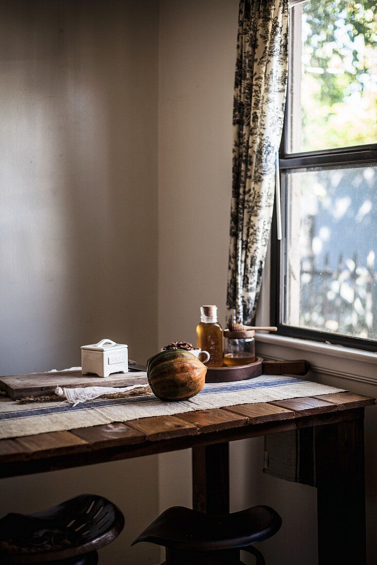 Ein Eichelkürbis auf rustikalem Tisch vor Fenster
