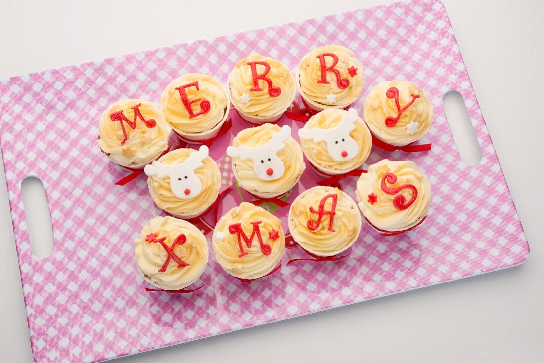 Cupcakes with icing spelling out 'Merry Xmas', on a tray