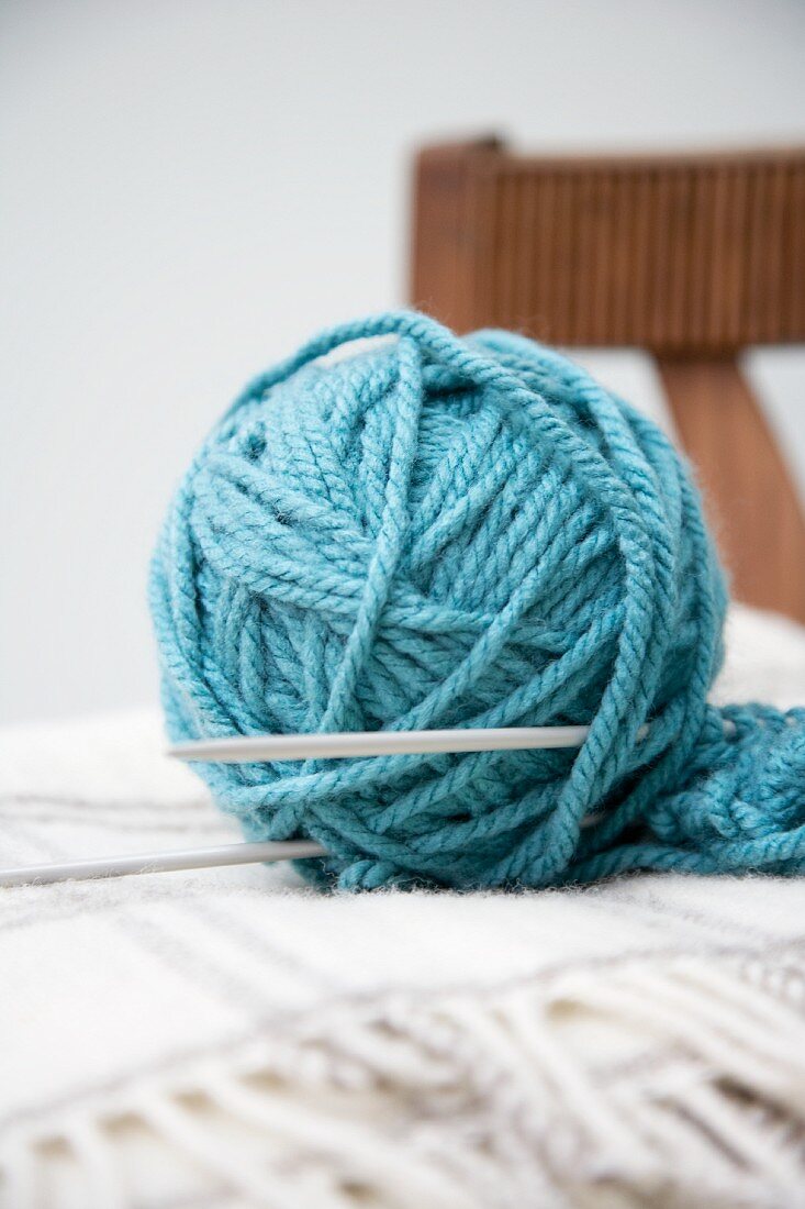 Ein blaues Wollknäuel mit Stricknadel