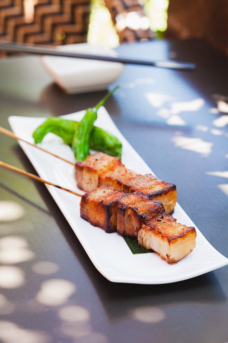 Skewers of Pork Belly on a White Plate