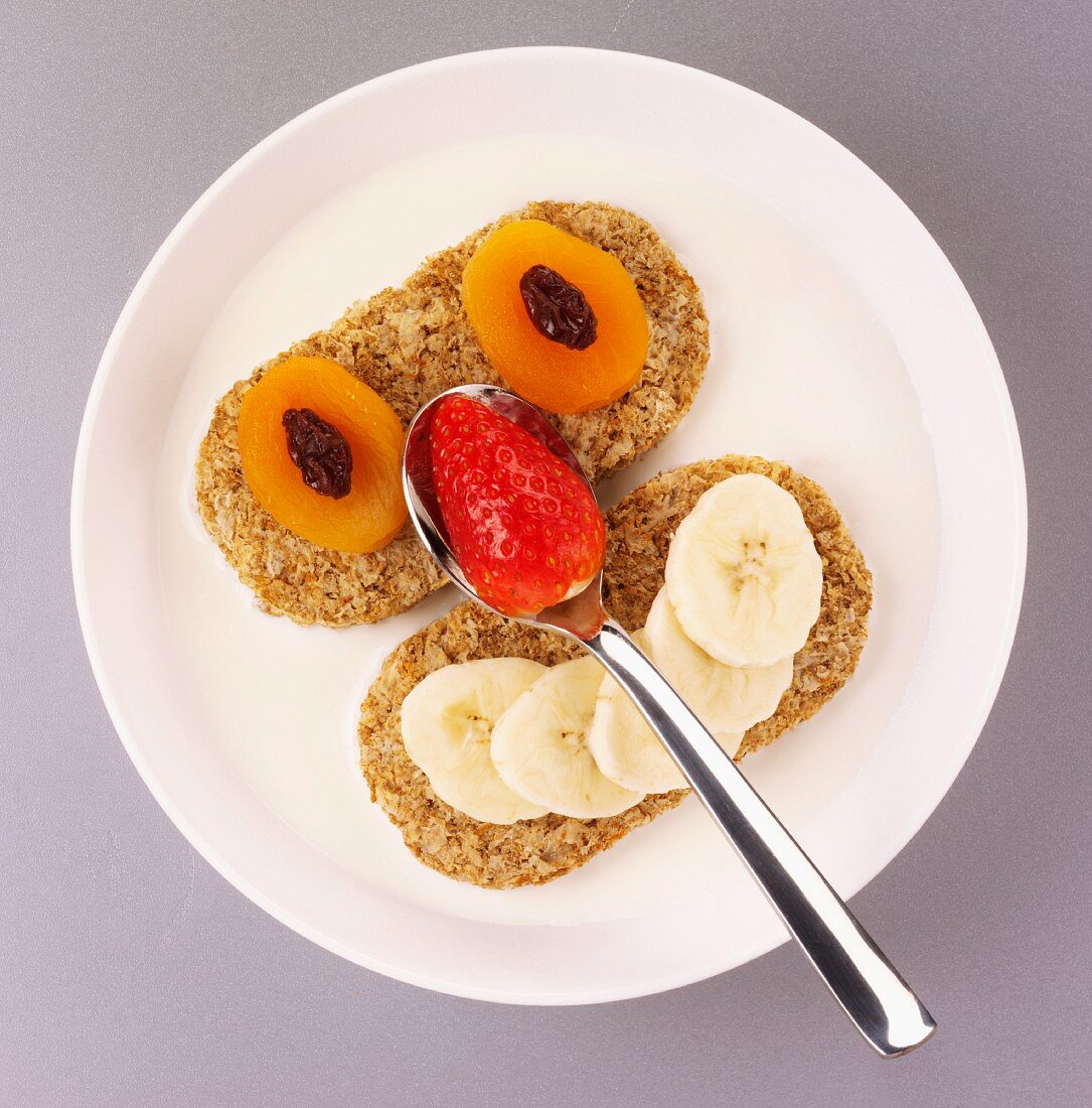 A face made of fruit, with dried apricots, strawberries and bananas on bread