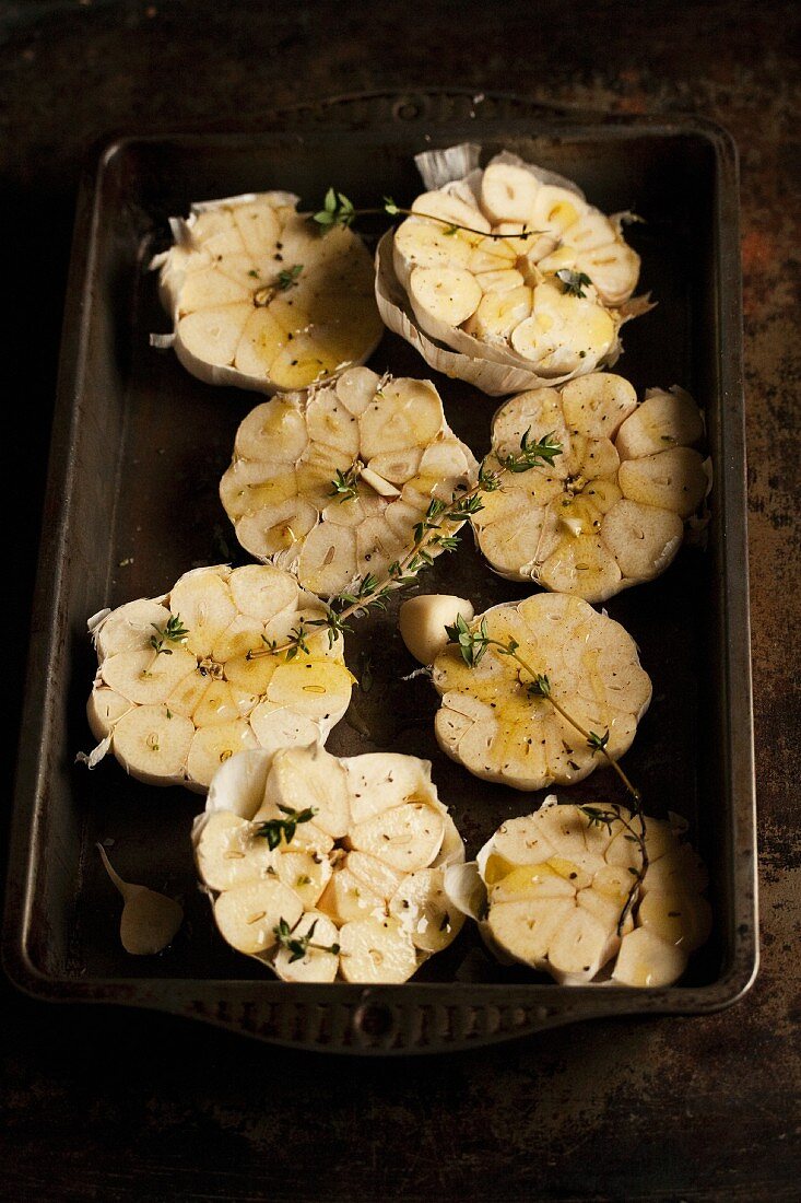 Garlic with thyme and olive oil on a baking tray