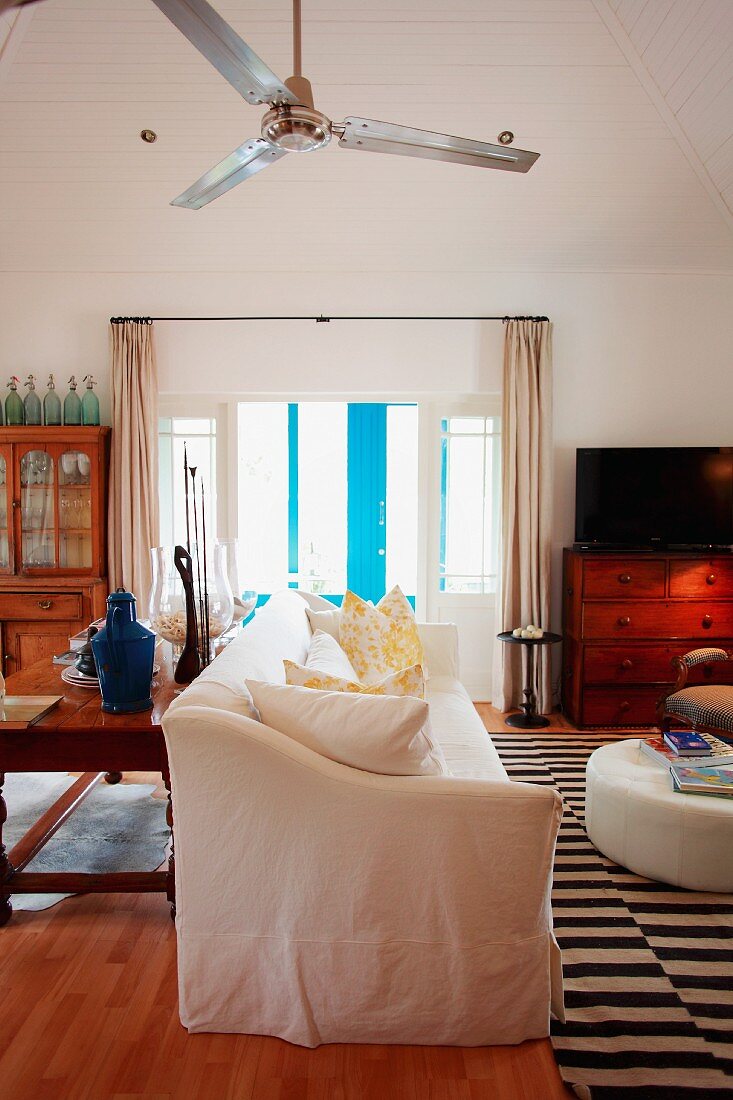 White sofa, wooden furniture & ceiling fan in living room