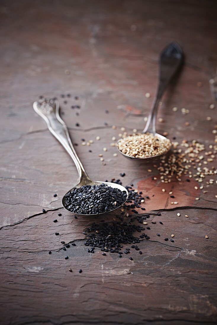 Two spoons of black and white sesame seeds