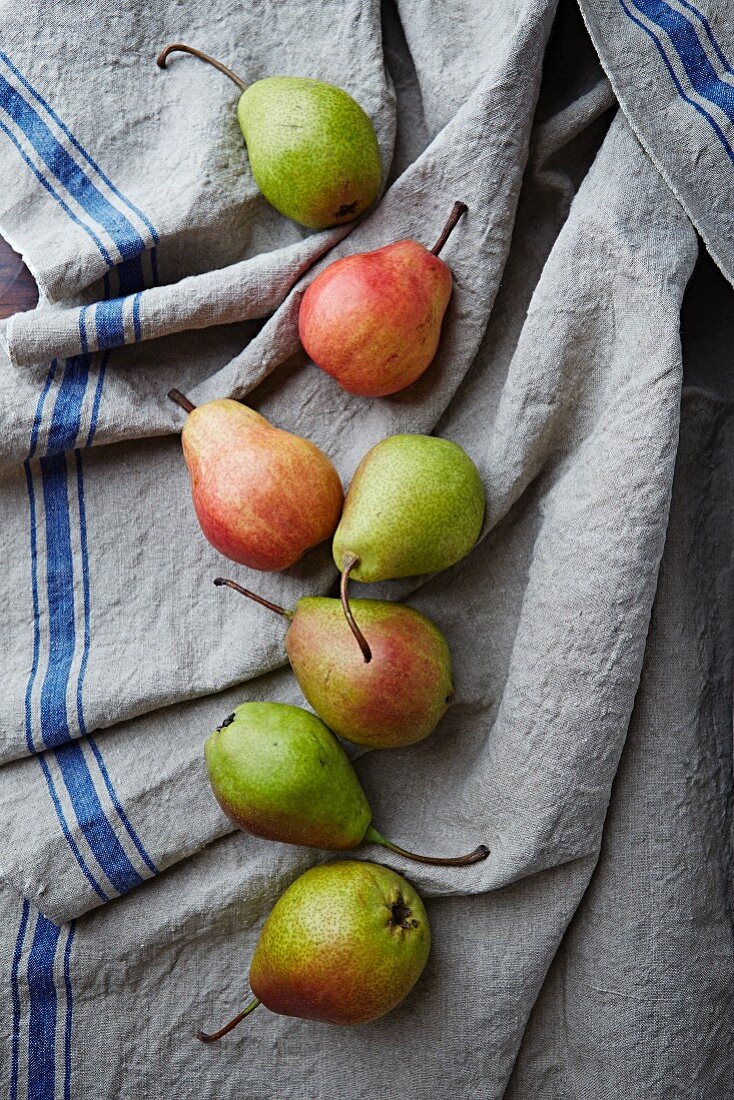Green and red pears on a linen cloth (view from above)