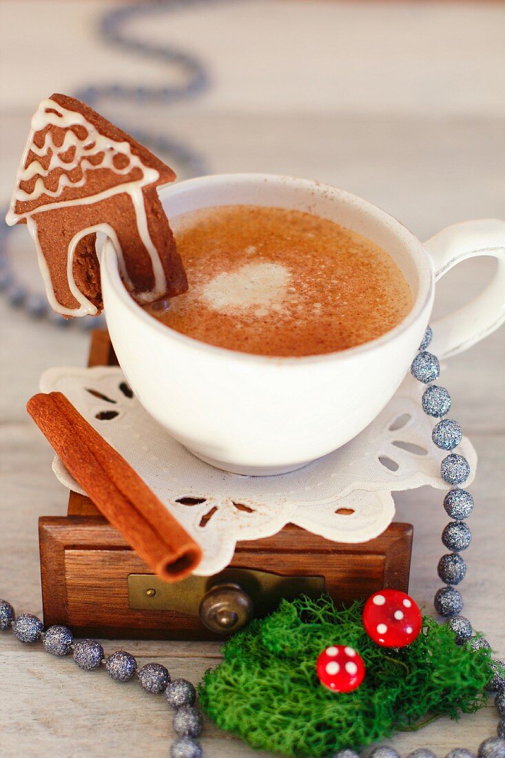 A cup of coffee with a mini gingerbread house for Christmas