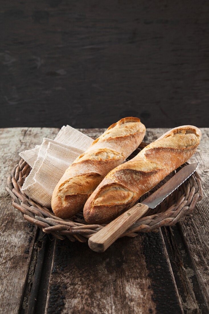 Baguettes in a basket with a knife