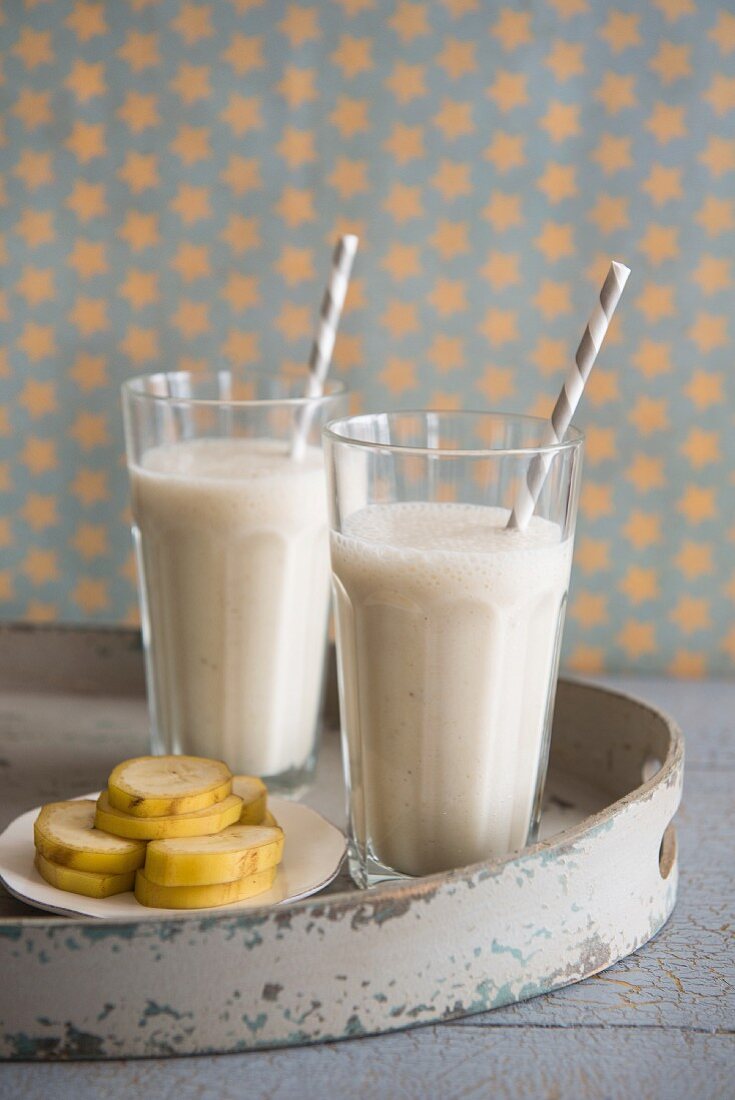 Two banana milkshakes in glasses with straws