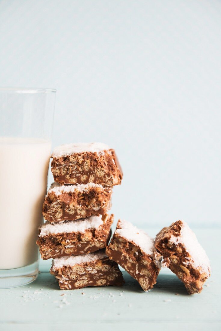 Crispy muesli squares with chocolate, stacked against a glass of milk