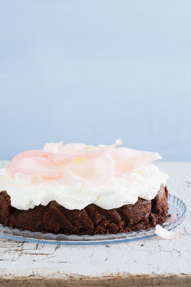 Mehlfreier Schokoladenkuchen mit Schlagsahne und Rosenblütenblättern