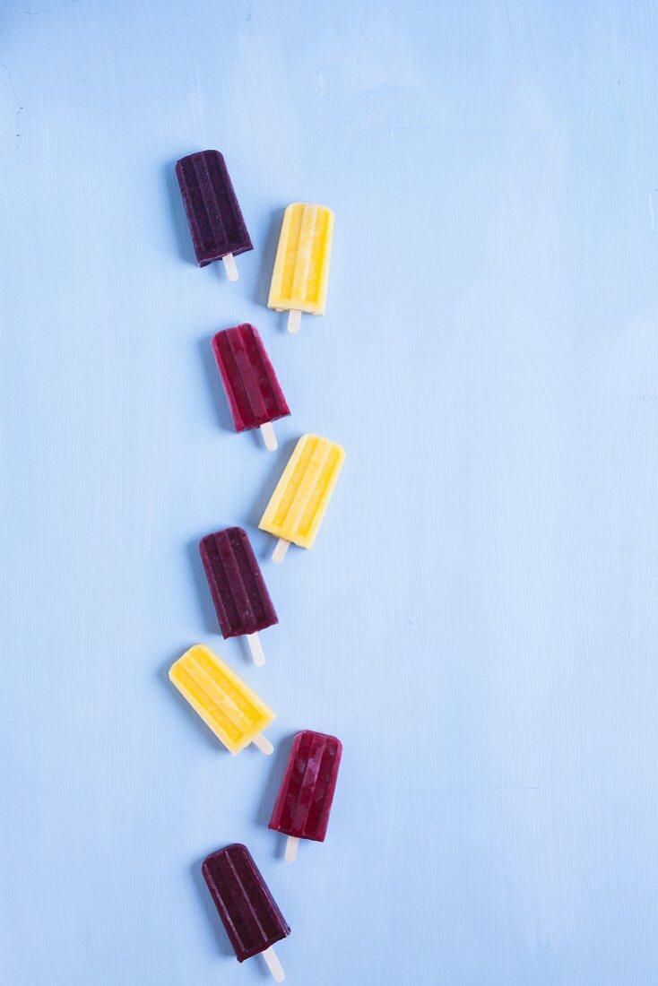 Blueberry, Rasberry and Mango Popsicles in a row