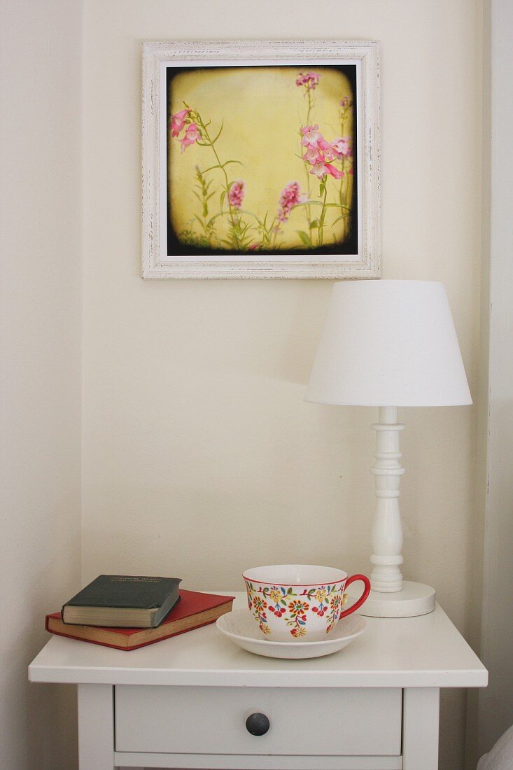 China teacup, books & table lamp on bedside cabinet