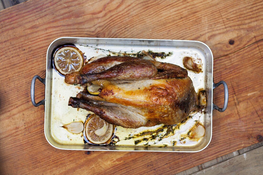 A whole roast chicken in the roasting tin (view from above)