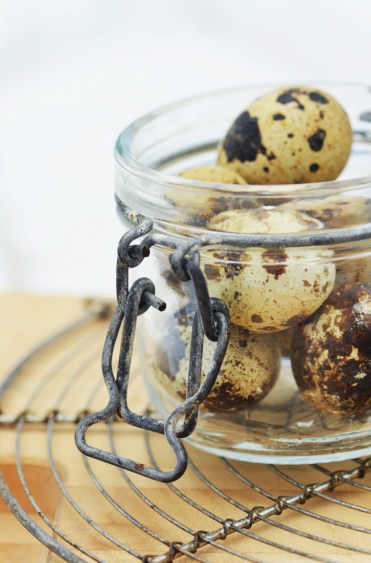 a glass jar filled with quails eggs on a vintage wire cooling rack
