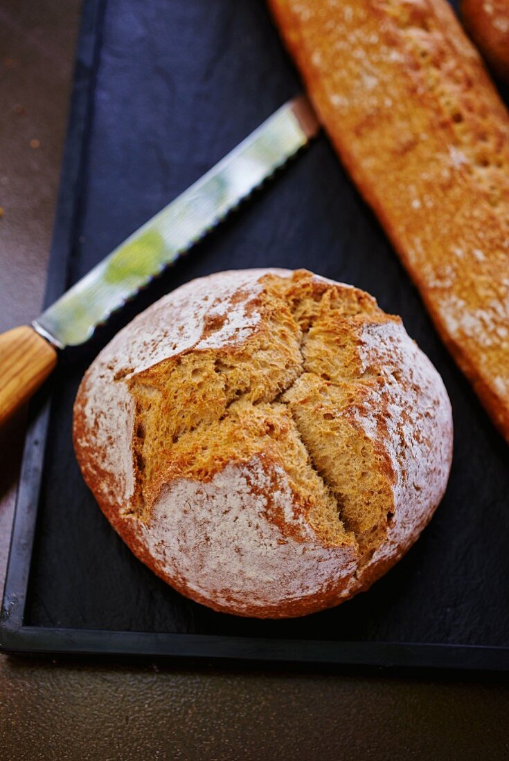 A loaf of crusty bread with a bread knife