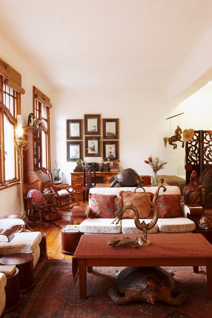 Coffee table and upholstered bench in living area with Oriental-style, metal animal sculptures