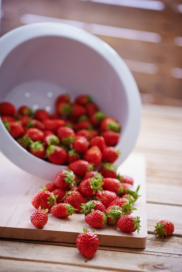 Fresh strawberries falling out of a colander
