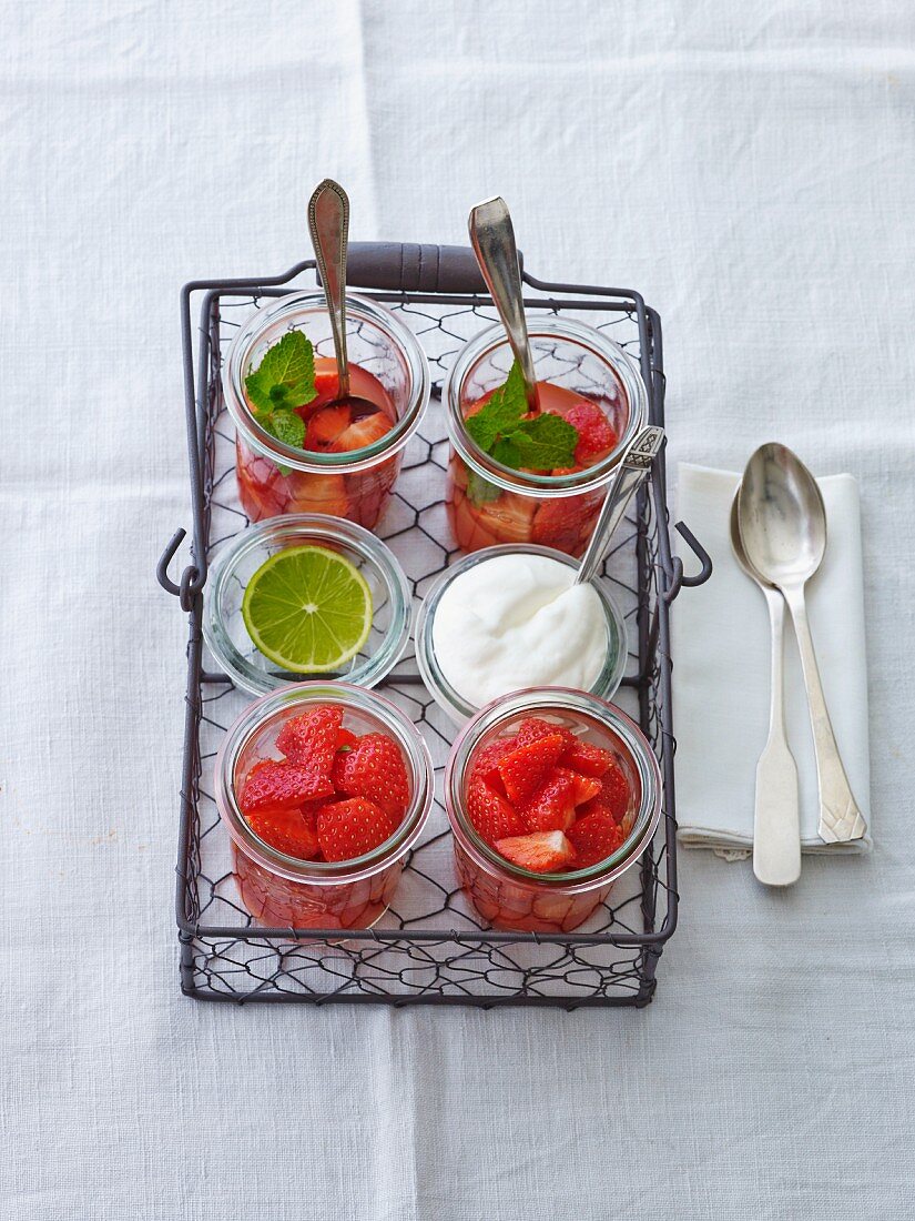 Fresh strawberries, cream and strawberry compote with mint in a wire basket