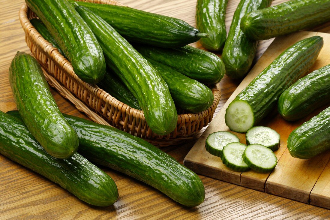 Fresh cucumbers in a basket and on a chopping board