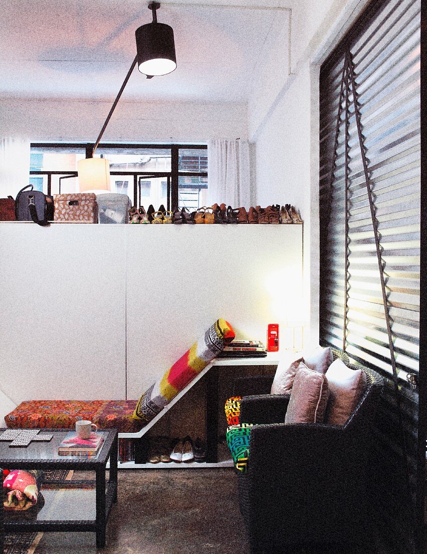 Cosy corner of loft apartment next to white partition with collection of shoes arranged on top