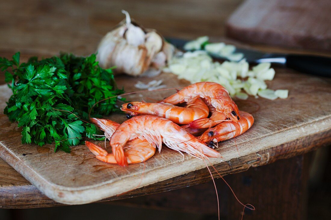 Whole king prawns, parsley and garlic on a chopping board