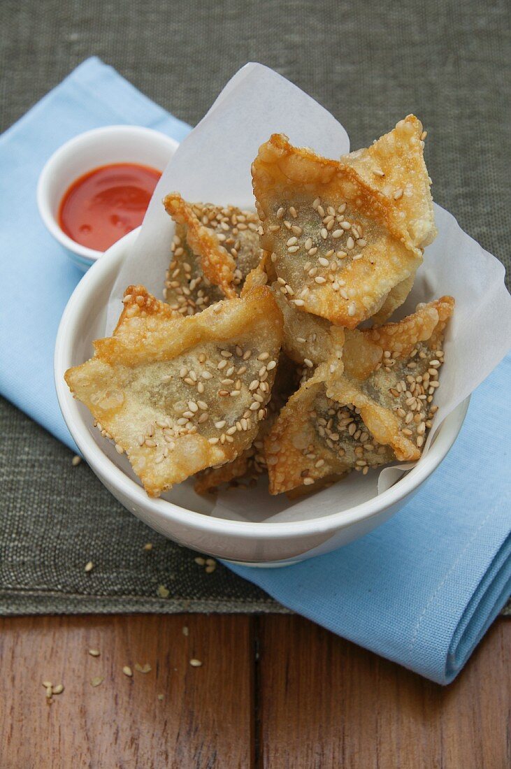 Deep-fried pastry parcels with sesame seeds and chilli sauce (Asia)