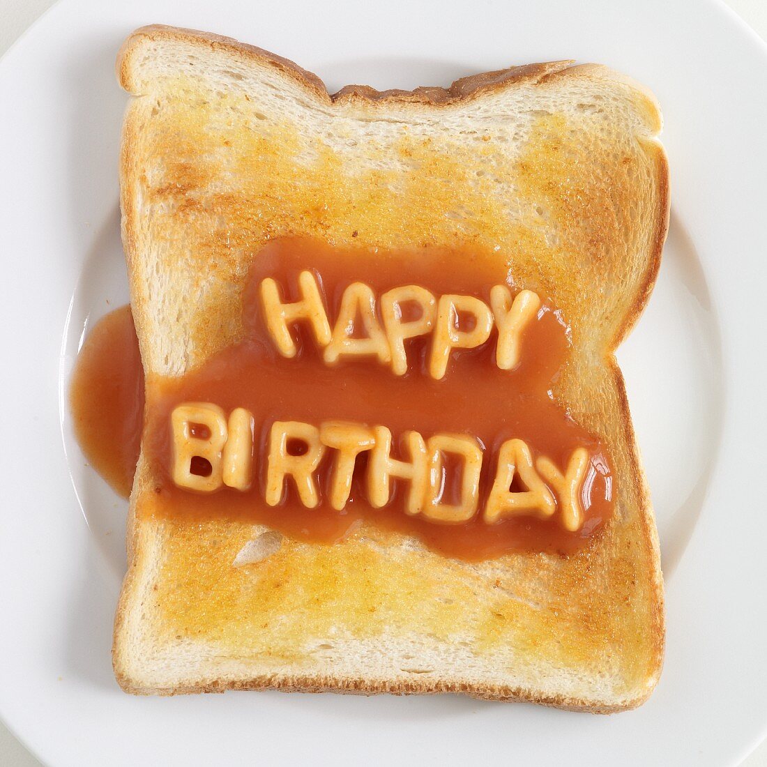 Toast topped with spaghetti letters spelling out HAPPY BIRTHDAY