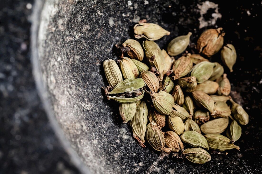 Cardamom pods in a stone mortar (close-up)