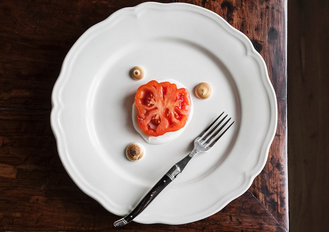 A fried slice of tomato on yoghurt with mini meringues