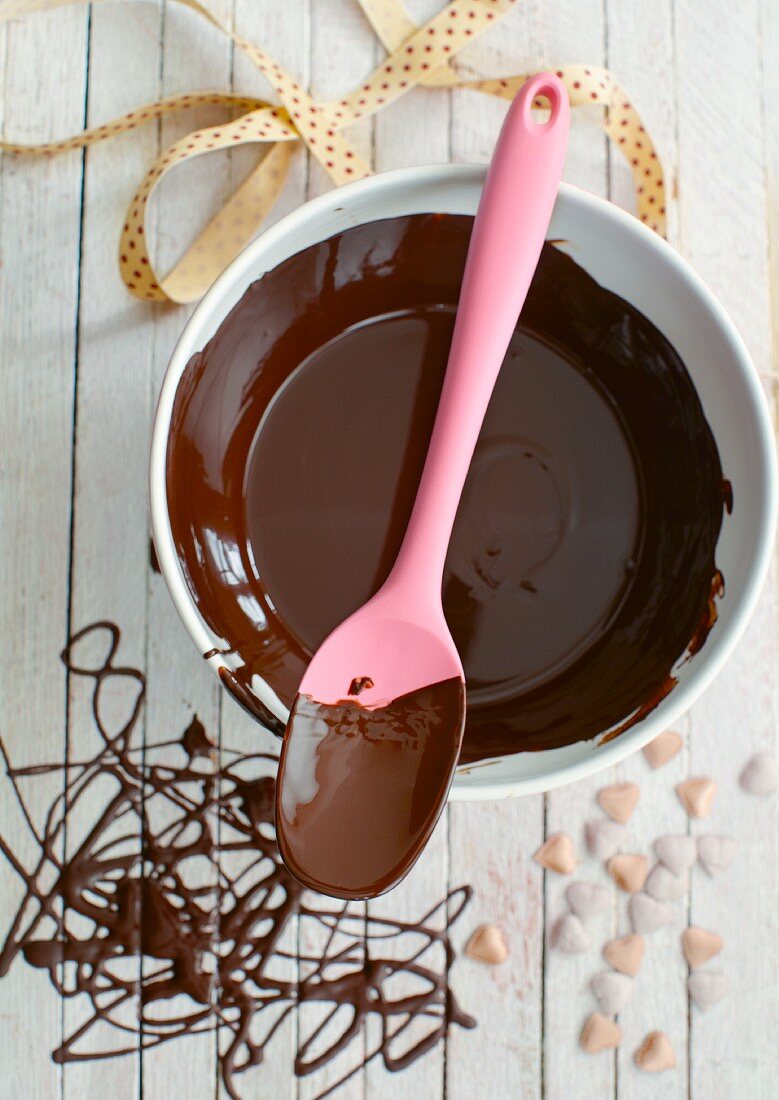 Schokoladensauce in Schale mit Kochlöffel (Draufsicht)