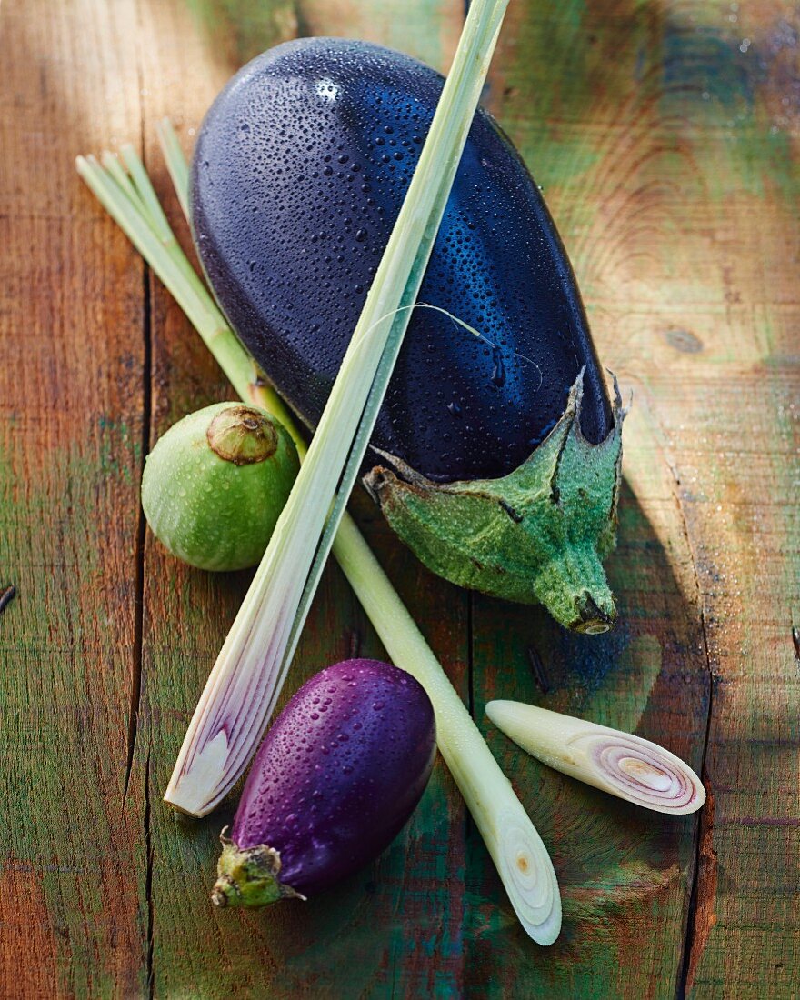 Assorted aubergines and lemongrass on a wooden surface