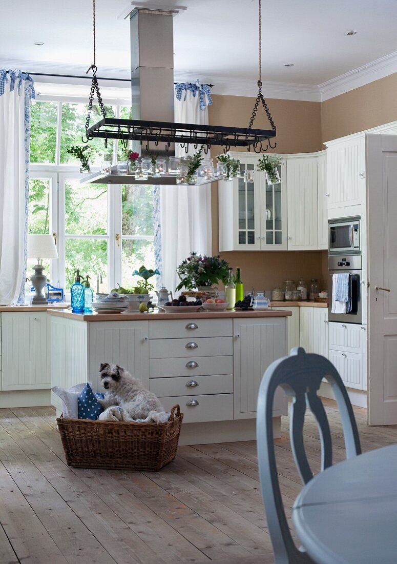 Helle Landhausküche mit Küchenblock, naturbelassenem Dielenboden und hellblauem Esstisch