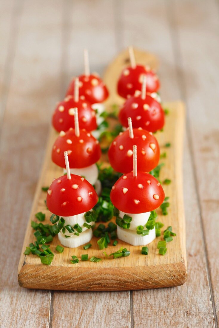Toadstools made from cherry tomatoes and mozzarella, with sliced chives and spots of mayonnaise