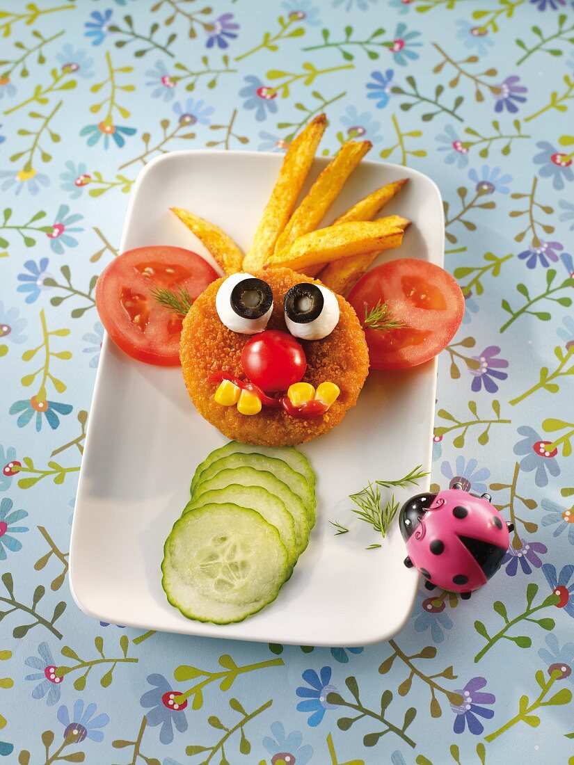 Breaded escalope of meat for a child, with a face made out of vegetables and chips