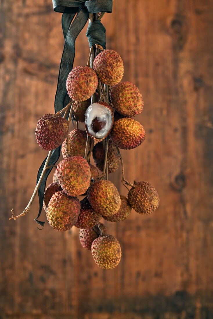 Lychees on a twig in front of a wooden wall