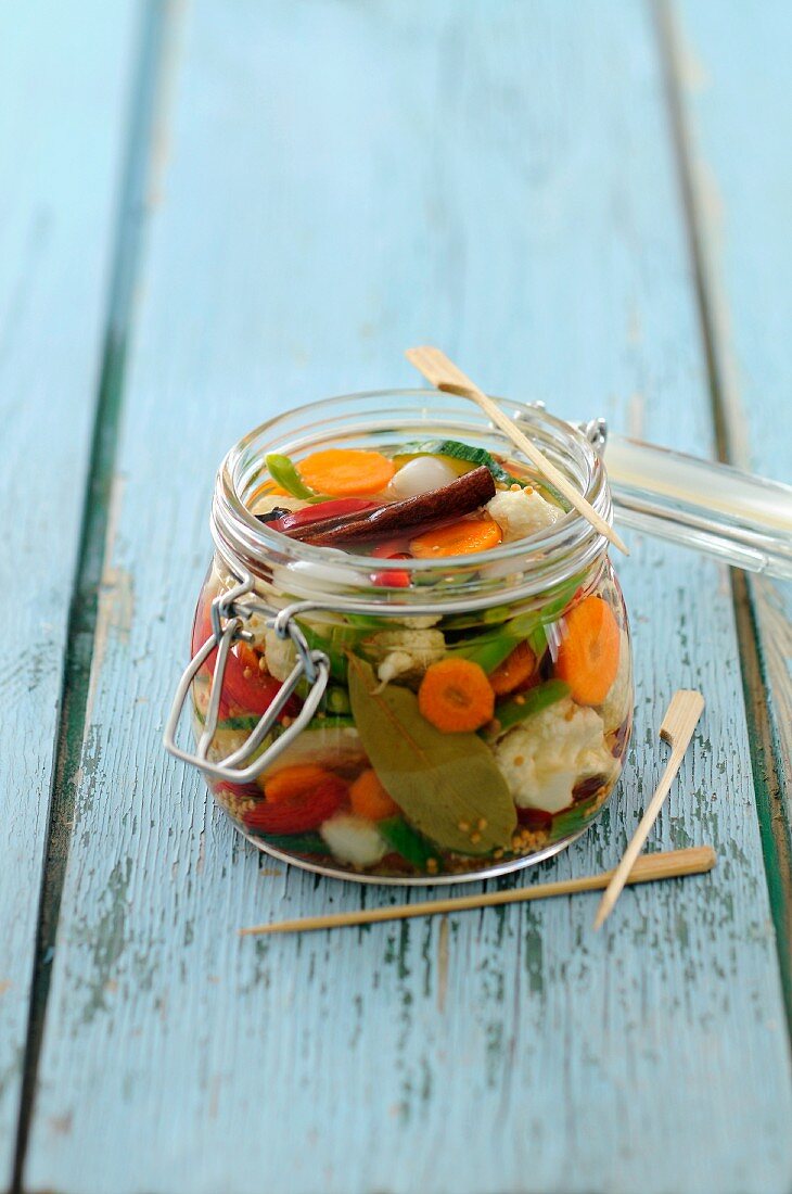A jar of pickled vegetables with cinnamon and bay leaves