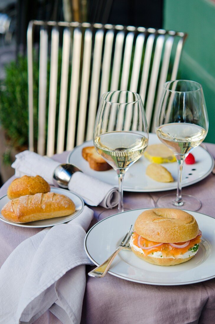 A table laid with bagels, rolls and white wine