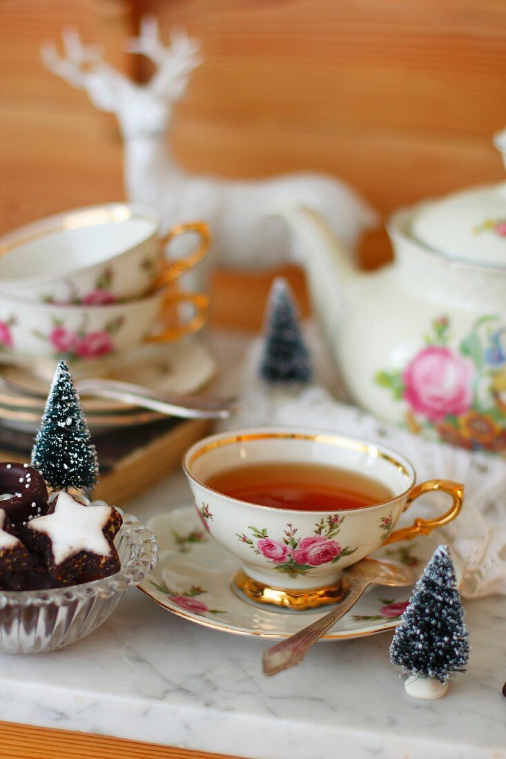 A cup of tea with a rose pattern and Christmas biscuits