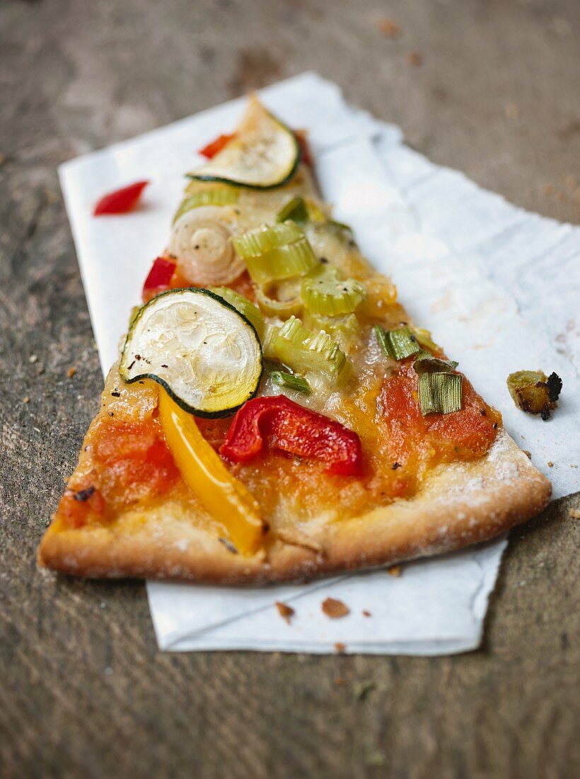 Ein Stück Gemüsepizza mit Zucchini und Paprika