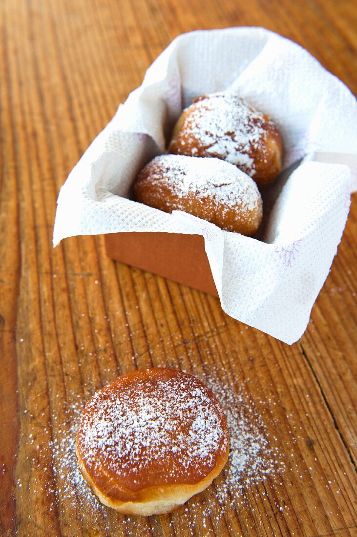 Doughnuts with icing sugar in and in front of a box