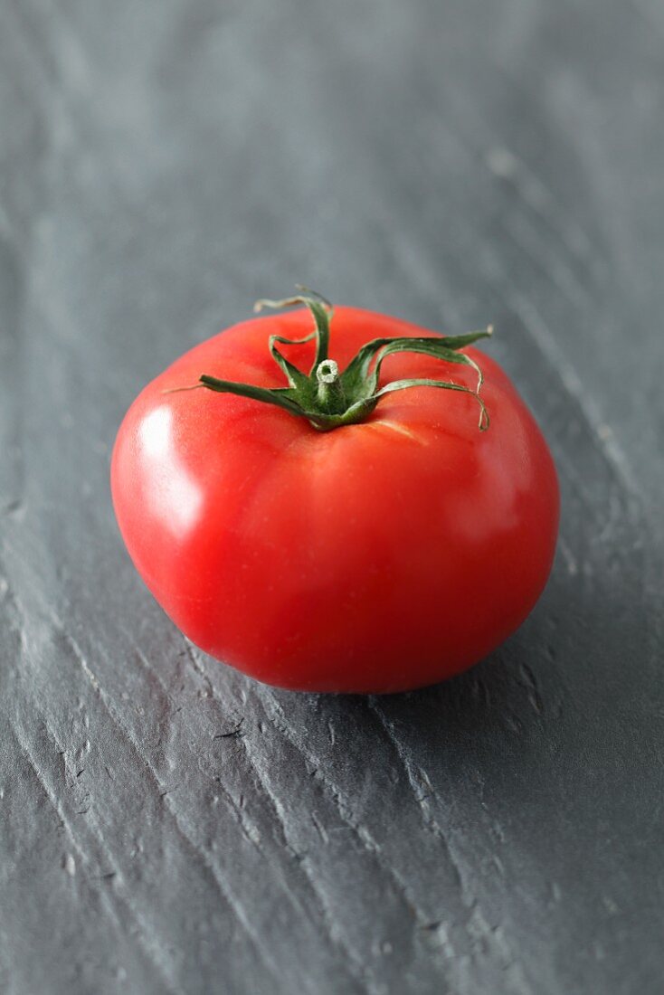 Eine Tomate auf grauem Untergrund